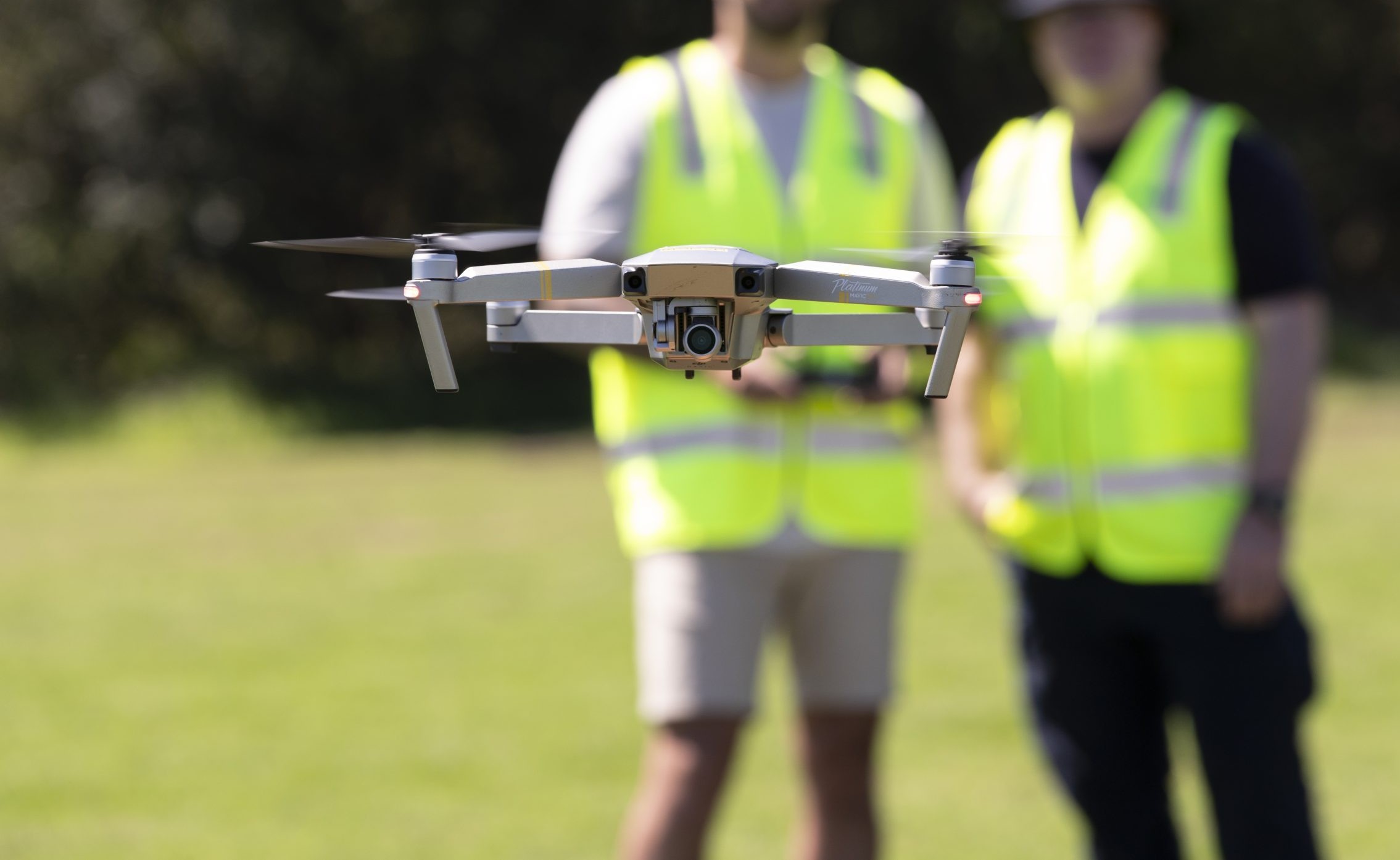 Two people standing there flying a drone